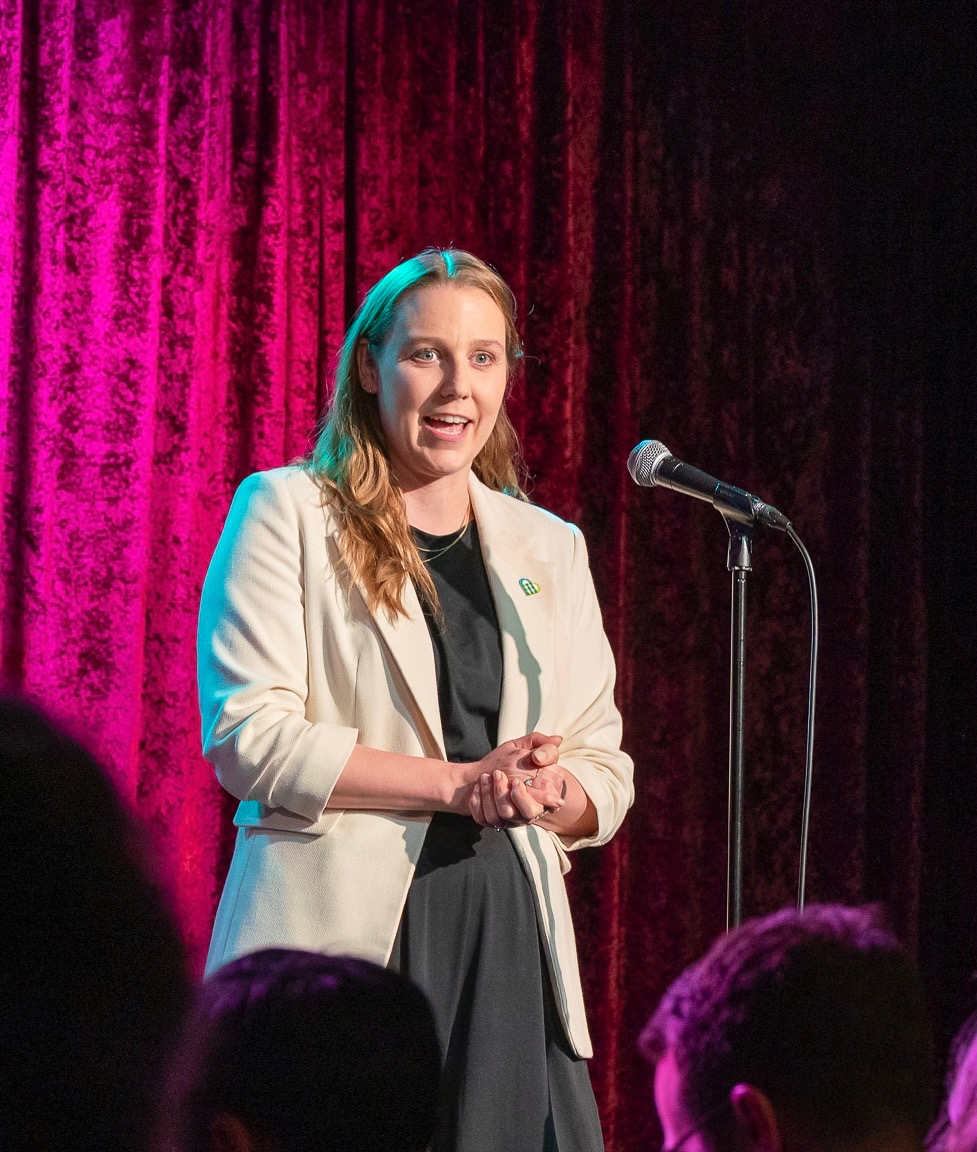 Claire speaking at a microphone